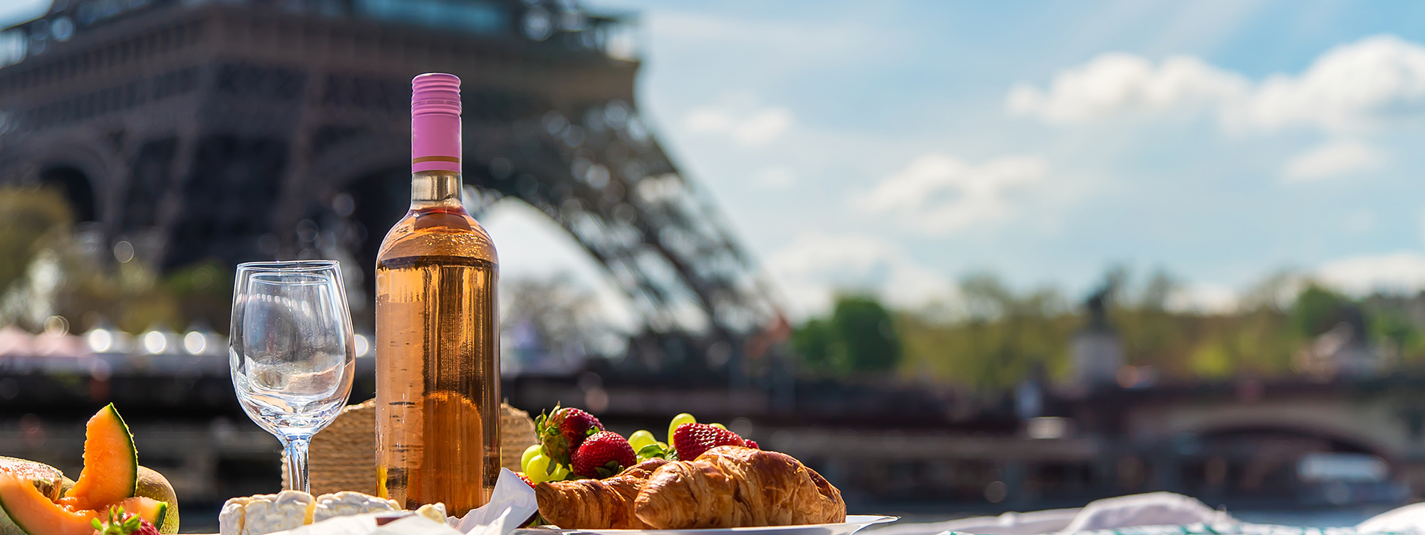 Reistips Parijs: Een romantische picknick met rosé, croissants en fruit bij de Eiffeltoren.